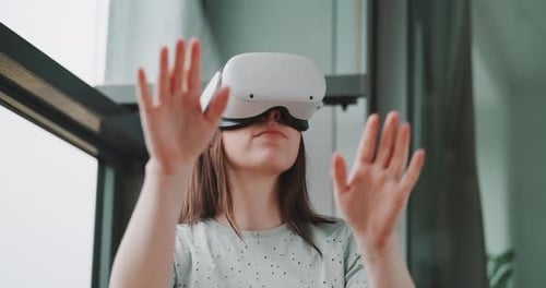Close up of woman wearing vr goggles and reaching toward lens direction with hands