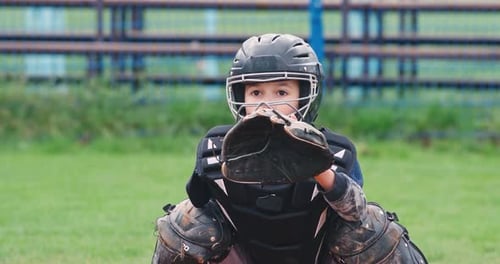 Portrait of a Boy Baseball Player on a Blurry Background, the Catcher in Protective Gear Catches a