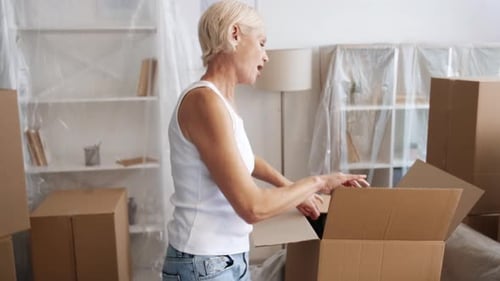 Woman Unpacks Clothes in Moving Boxes