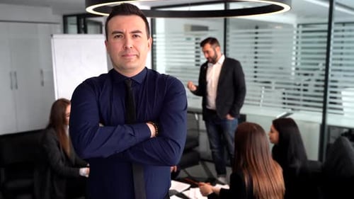 Confident Leader Stands Before Team in Modern Office