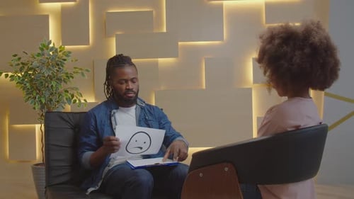 Afrikanischer männlicher Psychologe macht Psychotherapie mit Kind mit Emotionskarten