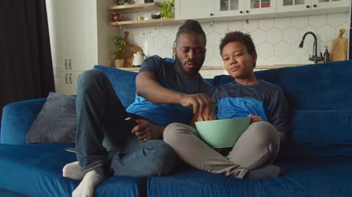 Father and Son Watching TV with Popcorn