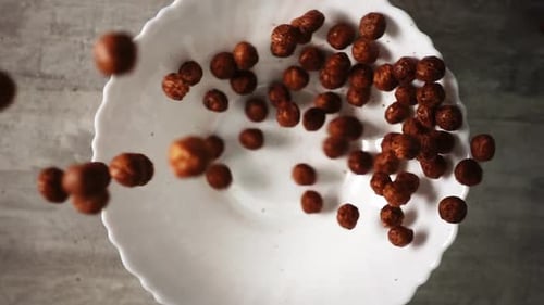 Chocolate Cereal Balls Falling Into a Bowl