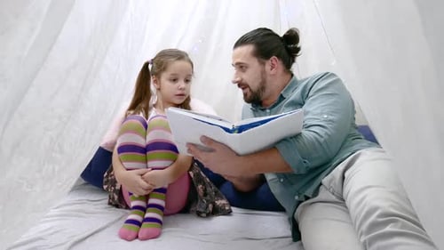 Man Reading Book with Child in a Tent