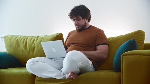 Man Using Laptop Computer on Green Couch Indoors