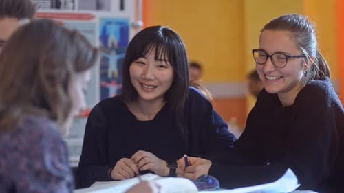 Multiethnic Students Study Together While Sitting at Desk in University Irrl.