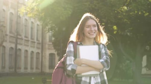 Smiling College Student Walking on Campus With Books