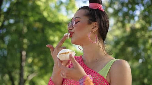 Jeune femme caucasienne coquette dans des vêtements rétro dégustant une délicieuse crème de beignet sucrée dans Slow