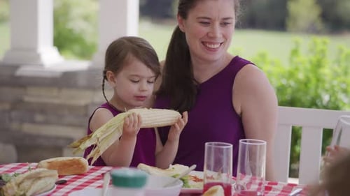 Girl and Woman Eating Corn on the Cob Outdoors