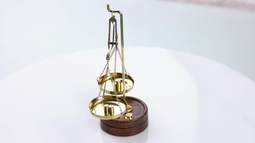 Balanced Brass Scales Rotate on White Table