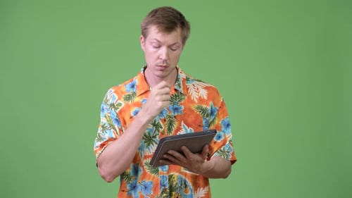Young Adult Contemplating a Tablet Against Green Screen