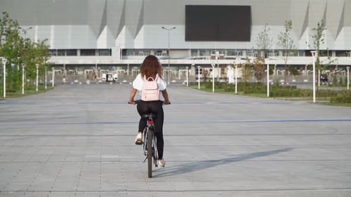 Beautiful young woman rides a bicycle in a city park on a summer day. Cyclist girl