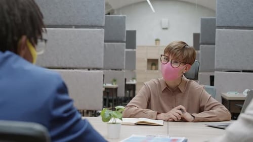 Three Colleagues Discuss Strategy at Modern Office Meeting