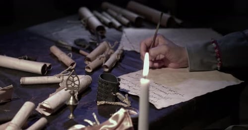 Person Writing with Quill by Candlelight in Dark Room