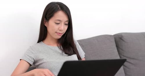 Woman Uses Laptop on Sofa in Bright Interior