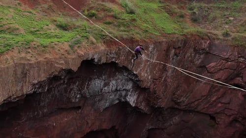 Person Tightrope Walking Between Rocky Cliffs