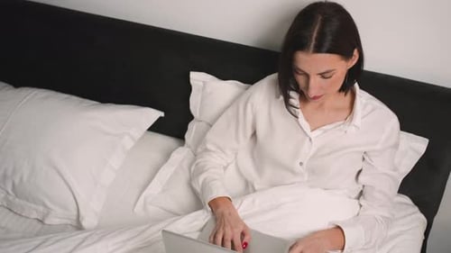 Woman Working on Laptop in Bed
