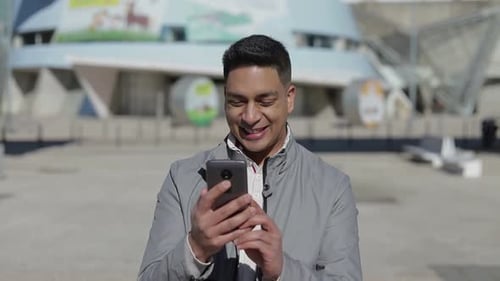 Smiling Man Using Smartphone in Urban Setting