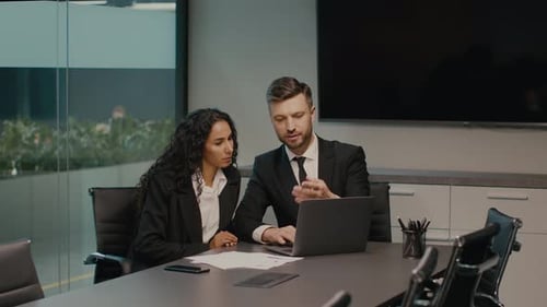 Two Colleagues Working On Laptop Discussing Business Project In Office