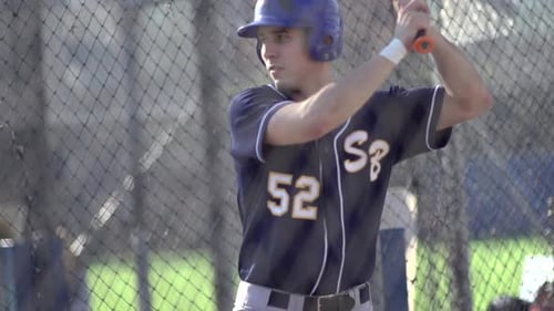 A young man practices baseball at the batting cages.