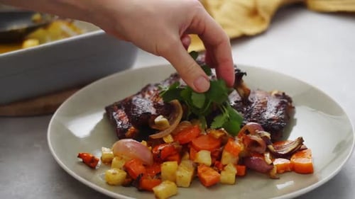 Crop person garnishing meat dish with cilantro