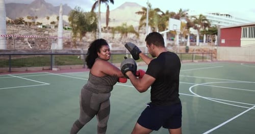 Woman Boxing with a Male Trainer Outdoors