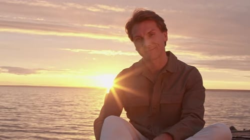 Portrait of Young Man Sitting near Ocean