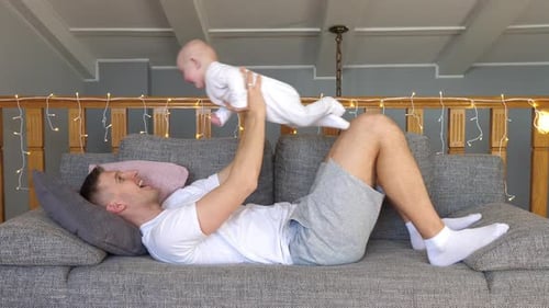 Father Plays with Baby on Couch