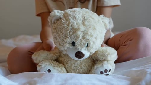 A little girl is holding a teddy bear.