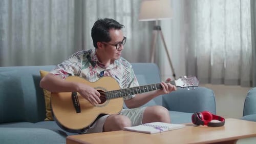 Young Adult Playing Acoustic Guitar at Home