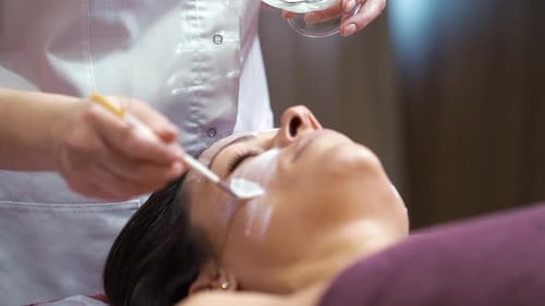 Cosmetóloga aplicando crema en la cara de una clienta en un spa de belleza