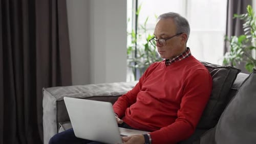 Senior Man Using Laptop Computer on Couch