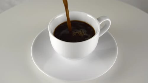Coffee Being Poured Into Cup on White Table