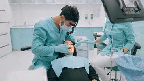 Dentist with Nurse and Patient in Dentist Office. A Patient Getting Dental Treatment at Dental