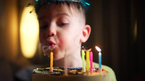 Boy With Party Hat Blows Out Birthday Candles