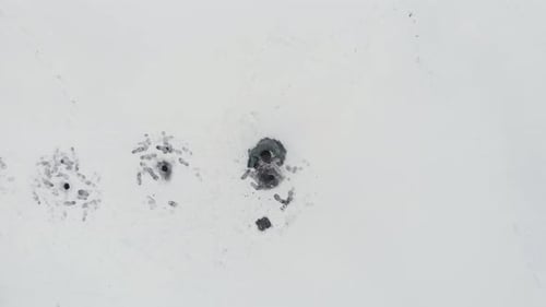 Fisherman is sitting on ice lake near ice hole