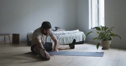 Man Stretching Legs on Yoga Mat Indoors