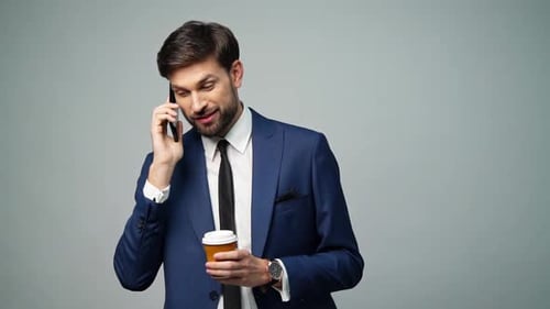 Man in Suit Talking on Phone with Coffee