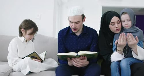 Muslim Family Reading Quran and Praying Together on the Sofa