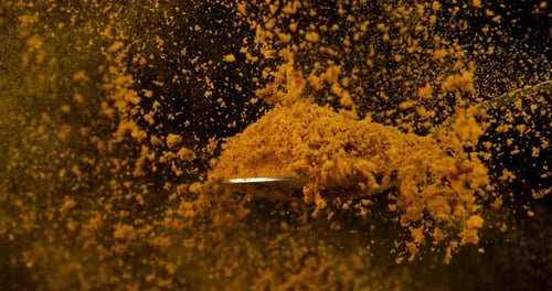 Spoon and Curry Powder falling against Black Background, Slow motion 4K