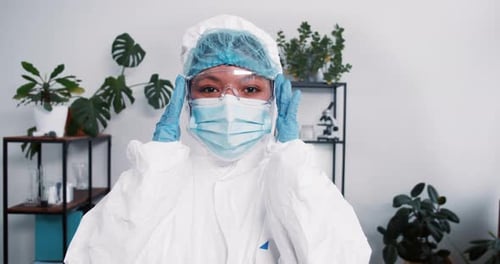Woman in Protective Suit Adjusts Goggles Indoors