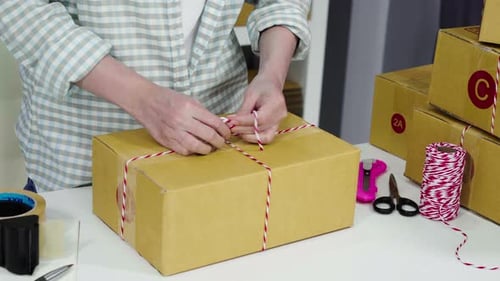 Woman Tying String Around a Cardboard Box