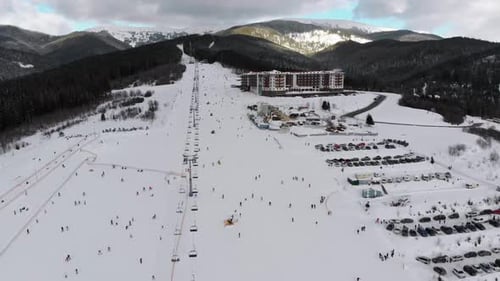 Vue aérienne d'un grand nombre de personnes skiant sur les pistes de ski près des remontées mécaniques de la station de ski