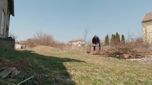 Man Chopping Firewood with Axe in Yard