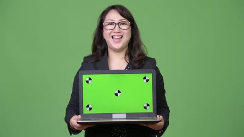 Mature Beautiful Asian Businesswoman Showing Laptop Against Green Background