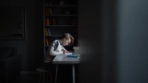 Side View of Pupil Boy in Wireless Earphone Learning Online Using Laptop Making Notes in Copybook