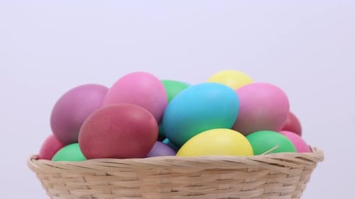 Bunte Oster-Hühnereier, die sich im Korb auf hellem Hintergrund drehen