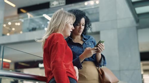 Two Women Looking at a Phone in Urban Space
