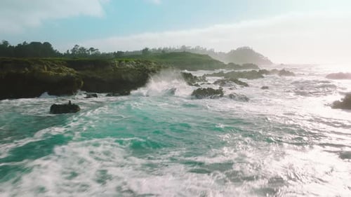 Vista aérea superior do oceano: ondas azuis quebram em praia rochosa, ondas do mar e penhascos