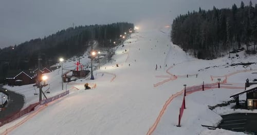 Aerial View of Ski Slopes with Skiers and Ski Lifts on Ski Resort in Winter Forest Against Snowy